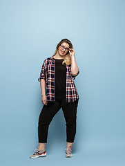 Image showing Young caucasian woman in casual wear on blue background. Bodypositive female character, plus size businesswoman