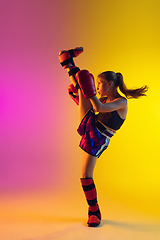 Image showing Little caucasian female kick boxer training on gradient background in neon light, active and expressive