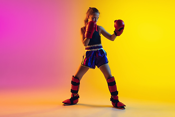 Image showing Little caucasian female kick boxer training on gradient background in neon light, active and expressive