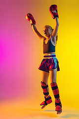 Image showing Little caucasian female kick boxer training on gradient background in neon light, active and expressive