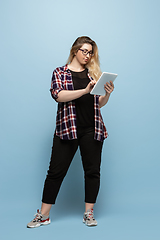 Image showing Young caucasian woman in casual wear on blue background. Bodypositive female character, plus size businesswoman