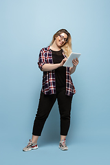 Image showing Young caucasian woman in casual wear on blue background. Bodypositive female character, plus size businesswoman