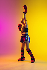 Image showing Little caucasian female kick boxer training on gradient background in neon light, active and expressive