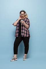 Image showing Young caucasian woman in casual wear on blue background. Bodypositive female character, plus size businesswoman