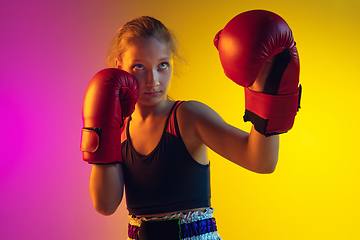 Image showing Little caucasian female kick boxer training on gradient background in neon light, active and expressive