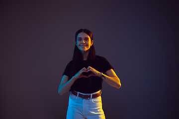 Image showing Caucasian young woman\'s portrait on dark background in neon light