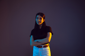 Image showing Caucasian young woman\'s portrait on dark background in neon light