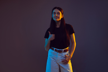 Image showing Caucasian young woman\'s portrait on dark background in neon light