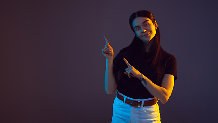 Image showing Caucasian young woman\'s portrait on dark background in neon light