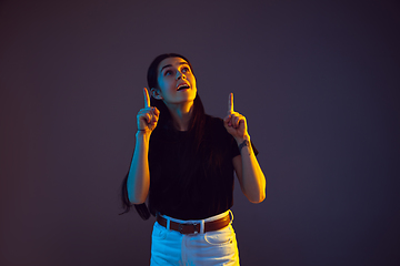 Image showing Caucasian young woman\'s portrait on dark background in neon light