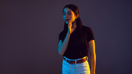 Image showing Caucasian young woman\'s portrait on dark background in neon light