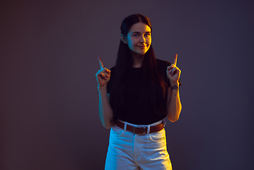 Image showing Caucasian young woman\'s portrait on dark background in neon light