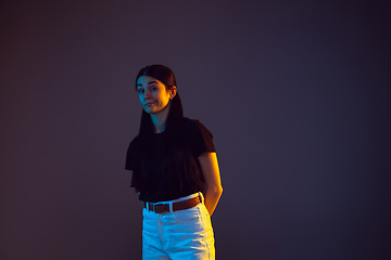 Image showing Caucasian young woman\'s portrait on dark background in neon light