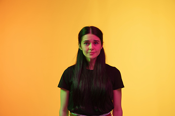 Image showing Caucasian young woman\'s portrait on yellow background in neon light