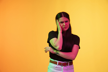 Image showing Caucasian young woman\'s portrait on yellow background in neon light