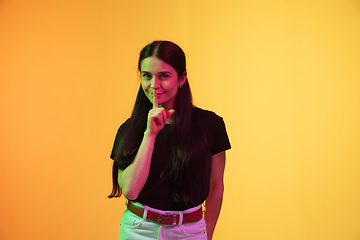 Image showing Caucasian young woman\'s portrait on yellow background in neon light