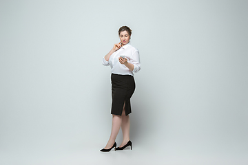 Image showing Young caucasian woman in office attire on gray background. Bodypositive female character. plus size businesswoman