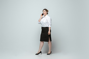 Image showing Young caucasian woman in office attire on gray background. Bodypositive female character. plus size businesswoman