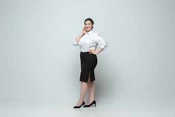 Image showing Young caucasian woman in office attire on gray background. Bodypositive female character. plus size businesswoman