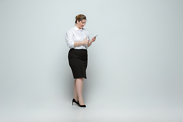 Image showing Young caucasian woman in office attire on gray background. Bodypositive female character. plus size businesswoman