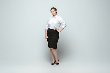 Image showing Young caucasian woman in office attire on gray background. Bodypositive female character. plus size businesswoman