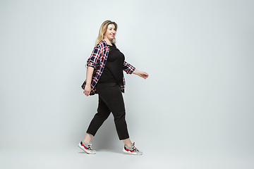 Image showing Young caucasian woman in casual wear on gray background. Bodypositive female character, plus size businesswoman