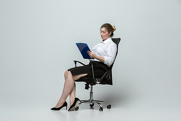 Image showing Young caucasian woman in office attire on gray background. Bodypositive female character. plus size businesswoman