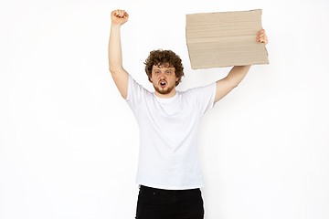 Image showing Young man protesting with blank board, sign isolated on white studio background