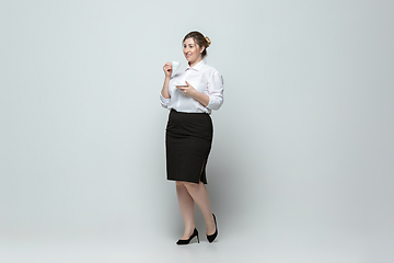 Image showing Young caucasian woman in office attire on gray background. Bodypositive female character. plus size businesswoman