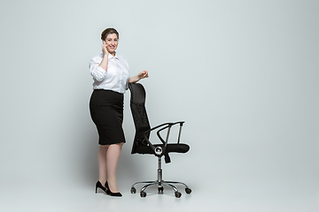 Image showing Young caucasian woman in office attire on gray background. Bodypositive female character. plus size businesswoman