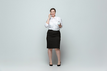 Image showing Young caucasian woman in office attire on gray background. Bodypositive female character. plus size businesswoman