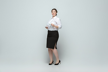 Image showing Young caucasian woman in office attire on gray background. Bodypositive female character. plus size businesswoman