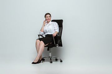 Image showing Young caucasian woman in office attire on gray background. Bodypositive female character. plus size businesswoman