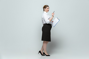 Image showing Young caucasian woman in office attire on gray background. Bodypositive female character. plus size businesswoman