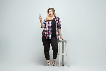 Image showing Young caucasian woman in casual wear on gray background. Bodypositive female character, plus size businesswoman