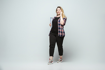 Image showing Young caucasian woman in casual wear on gray background. Bodypositive female character, plus size businesswoman