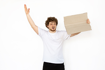 Image showing Young man protesting with blank board, sign isolated on white studio background