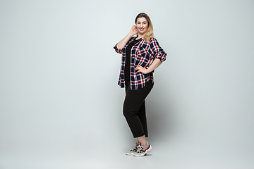 Image showing Young caucasian woman in casual wear on gray background. Bodypositive female character, plus size businesswoman