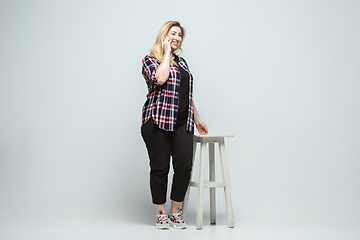 Image showing Young caucasian woman in casual wear on gray background. Bodypositive female character, plus size businesswoman