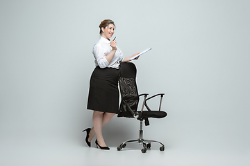 Image showing Young caucasian woman in office attire on gray background. Bodypositive female character. plus size businesswoman