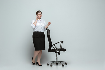 Image showing Young caucasian woman in office attire on gray background. Bodypositive female character. plus size businesswoman