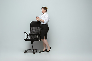 Image showing Young caucasian woman in office attire on gray background. Bodypositive female character. plus size businesswoman