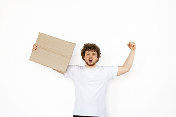 Image showing Young man protesting with blank board, sign isolated on white studio background