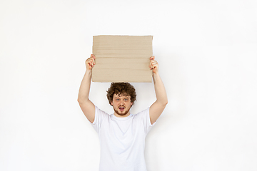 Image showing Young man protesting with blank board, sign isolated on white studio background