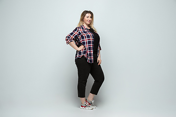 Image showing Young caucasian woman in casual wear on gray background. Bodypositive female character, plus size businesswoman