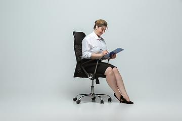 Image showing Young caucasian woman in office attire on gray background. Bodypositive female character. plus size businesswoman