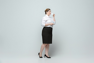 Image showing Young caucasian woman in office attire on gray background. Bodypositive female character. plus size businesswoman