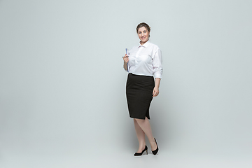 Image showing Young caucasian woman in office attire on gray background. Bodypositive female character. plus size businesswoman