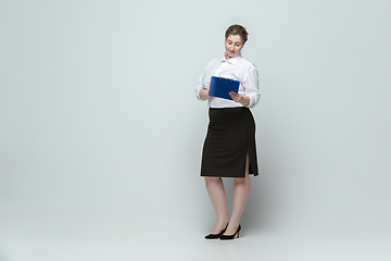 Image showing Young caucasian woman in office attire on gray background. Bodypositive female character. plus size businesswoman