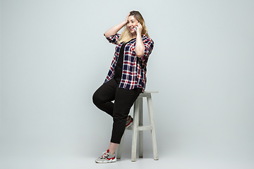 Image showing Young caucasian woman in casual wear on gray background. Bodypositive female character, plus size businesswoman